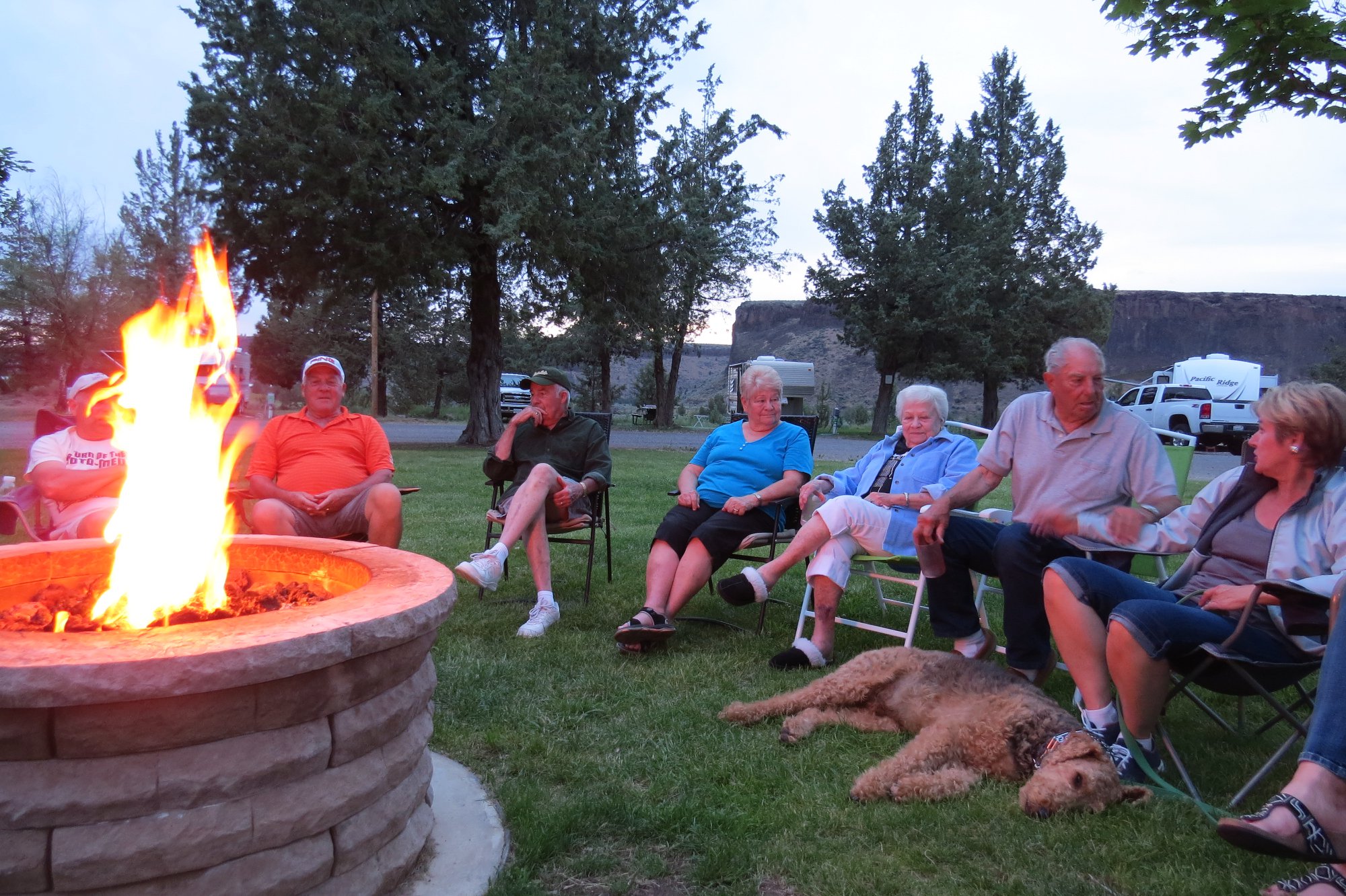 Guests gathered around the gas firepit at dusk with canyon rim in the background